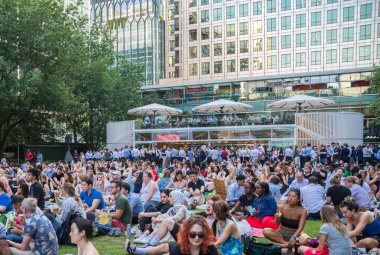 Londra, İngiltere - 30 Temmuz 2024: Bir sürü insanla Kanada meydanı, ofis çalışanları iş gününden sonra halka açık etkinliğin tadını çıkarıyorlar. İnsanlar kanarya iskelesinde film izler, içki içer ve piknik yapar.