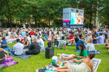 Londra, İngiltere - 30 Temmuz 2024: Bir sürü insanla Kanada meydanı, ofis çalışanları iş gününden sonra halka açık etkinliğin tadını çıkarıyorlar. İnsanlar kanarya iskelesinde film izler, içki içer ve piknik yapar.