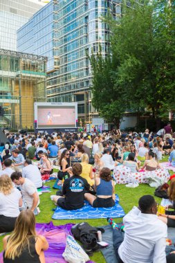 Londra, İngiltere - 30 Temmuz 2024: Bir sürü insanla Kanada meydanı, ofis çalışanları iş gününden sonra halka açık etkinliğin tadını çıkarıyorlar. İnsanlar kanarya iskelesinde film izler, içki içer ve piknik yapar.