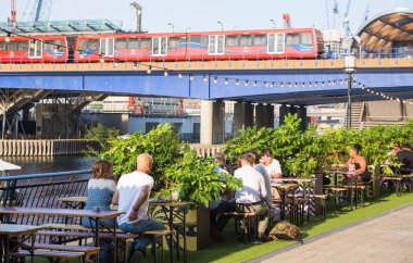 Londra, İngiltere - 30 Temmuz 2024: İnsanlar Canary Wharf 'ta çalıştıktan sonra halka açık bir kafede içki içiyorlar. 