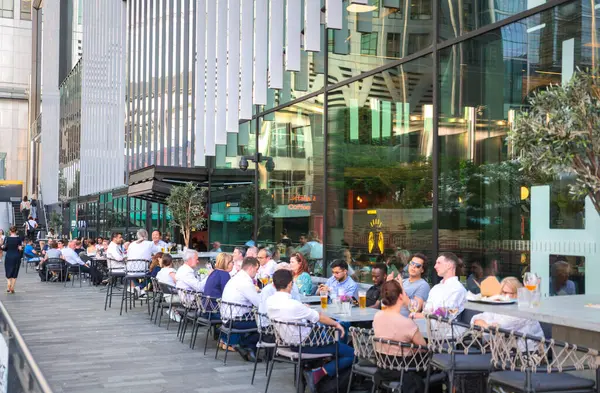 Londra, İngiltere - 30 Temmuz 2024: İnsanlar Canary Wharf 'ta çalıştıktan sonra halka açık bir kafede içki içiyorlar. 