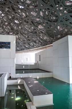 BAE, Abu Dabi - 22 Ağustos 2024: Louvre Abu Dabi avlusu Palmiye ağaçlarının gölgelerinden esinlenerek ünlü kubbe metal çatısı. 