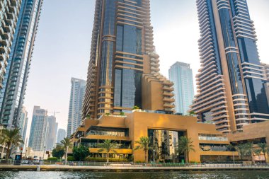 Dubai, BAE - 26 Ağustos 2024: Günbatımında Dubai Marina 'nın otelleri ve yerleşim yerleri. Tekneden panoramik görünüm