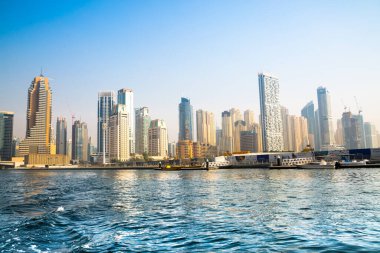 Dubai, BAE - 26 Ağustos 2024: Dubai Marina gökdelenleri gün batımında görülüyor. Tekneden panoramik görünüm