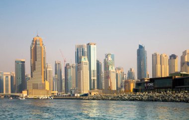 Dubai, BAE - 26 Ağustos 2024: Dubai Marina gökdelenleri gün batımında görülüyor. Tekneden panoramik görünüm