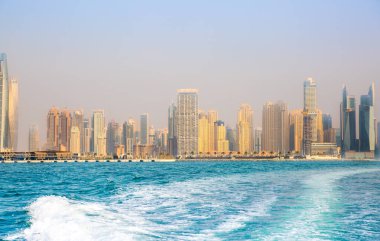 Dubai, BAE - 26 Ağustos 2024: Marina plajı, uzun oteller ve yerleşim yerleri. Tekneden panoramik görünüm