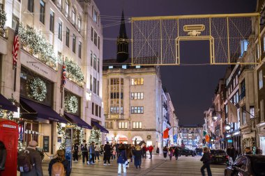 Londra, İngiltere - 8 Kasım 2024: Bond Caddesi 'nde Noel ışıkları. Londra Noel ve 2025 yılbaşı kutlamaları için aydınlatıldı. Kalabalık cadde, insanlar ışıkların tadını çıkarıyor ve alışveriş yapıyorlar. 