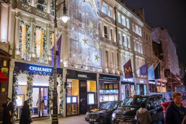 Londra, İngiltere - 8 Kasım 2024: Bond Caddesi 'nde Noel ışıkları. Londra Noel ve 2025 yılbaşı kutlamaları için aydınlatıldı. Kalabalık cadde, insanlar ışıkların tadını çıkarıyor ve alışveriş yapıyorlar. 