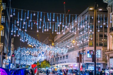 Londra, İngiltere - 8 Kasım 2024: Oxford sirkinde Noel ışıkları Noel ve 2025 yılbaşı kutlamaları için aydınlatıldı. Kalabalık cadde, insanlar ışıkların tadını çıkarıyor ve alışveriş yapıyorlar. 