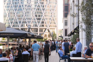 Londra, İngiltere - 30 Temmuz 2024: İnsanlar Canary Wharf 'ta çalıştıktan sonra barda içki içiyorlar. Gün batımında şehir merkezinde iş ve bankacılık
