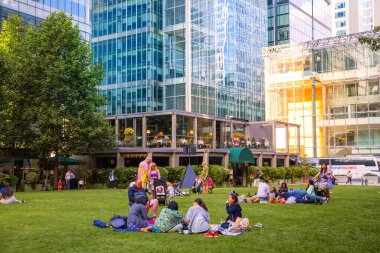 Londra, İngiltere - 14 Haziran 2025: Bir grup insan Kanada meydanında piknik yapıyor. Gün batımında Kanarya İskelesi.