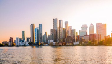 Londra, İngiltere - 18 Haziran 2025: Canary Wharf işletmesi ve Thames nehrinden günbatımında panoramik manzara.