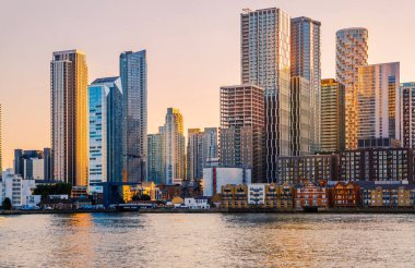 Londra, İngiltere - 18 Haziran 2025: Canary Wharf işletmesi ve Thames nehrinden günbatımında panoramik manzara.