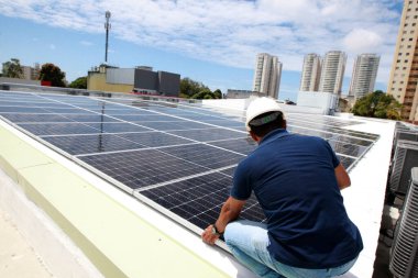 Salvador, Bahia, Brezilya - 21 Ekim 2022: Bir işçi Salvador kentindeki bir devlet okulunun çatısına güneş panelleri kuruyor.