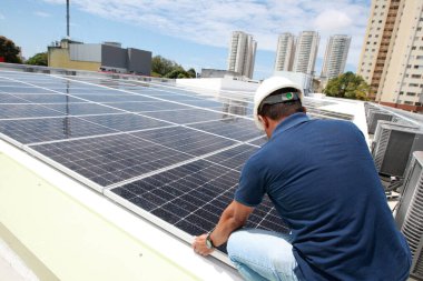 Salvador, Bahia, Brezilya - 21 Ekim 2022: Bir işçi Salvador kentindeki bir devlet okulunun çatısına güneş panelleri kuruyor.