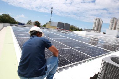 Salvador, Bahia, Brezilya - 21 Ekim 2022: Bir işçi Salvador kentindeki bir devlet okulunun çatısına güneş panelleri kuruyor.