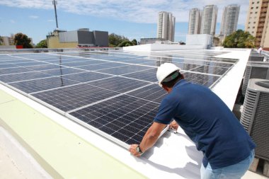Salvador, Bahia, Brezilya - 21 Ekim 2022: Bir işçi Salvador kentindeki bir devlet okulunun çatısına güneş panelleri kuruyor.