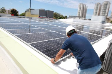 Salvador, Bahia, Brezilya - 21 Ekim 2022: Bir işçi Salvador kentindeki bir devlet okulunun çatısına güneş panelleri kuruyor.