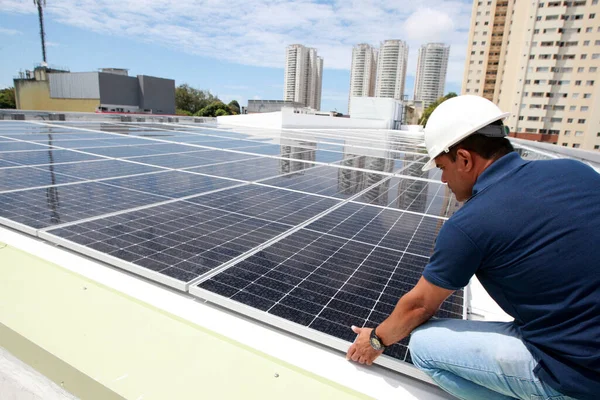 Salvador, Bahia, Brezilya - 21 Ekim 2022: Bir işçi Salvador kentindeki bir devlet okulunun çatısına güneş panelleri kuruyor.