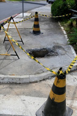 Salvador, Bahia, Brezilya - 16 Mayıs 2023: Koni ve güvenlik bandı Salvador şehrinin kaldırımında delik olan yerel işaret