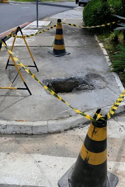 Salvador, Bahia, Brezilya - 16 Mayıs 2023: Koni ve güvenlik bandı Salvador şehrinin kaldırımında delik olan yerel işaret