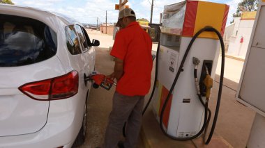 porto seguro, bahia, brazil - october 20, 2023: gas station attendant fills up gasoline and vehicle at a gas station clipart