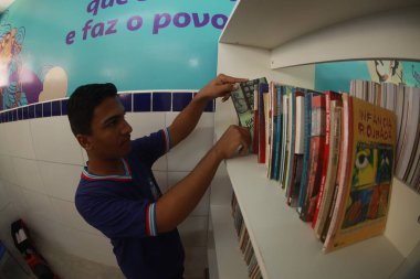 Tanhacu, Bahia, Brezilya - 31 Mayıs 2025: Bir okul kütüphanesinde devlet okulundan genç bir öğrenci, kitaplarını düzenliyor veya seçiyor..