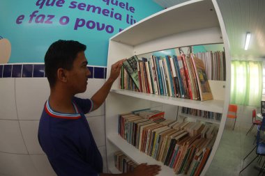 Tanhacu, Bahia, Brezilya - 31 Mayıs 2025: Bir okul kütüphanesinde devlet okulundan genç bir öğrenci, kitaplarını düzenliyor veya seçiyor..