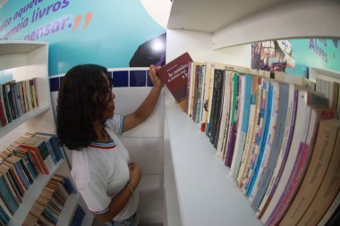 Tanhacu, Bahia, Brezilya - 31 Mayıs 2025: Bir okul kütüphanesinde devlet okulundan genç bir öğrenci, kitaplarını düzenliyor veya seçiyor..