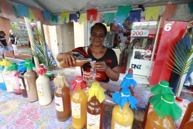 itapetinga, bahia, brrazil - 20 Haziran 2025: Renkli afişlerle süslenmiş bir tezgahta gülümseyen kadın tipik bir şenlik ve Sao Joao içkisi satıyor..