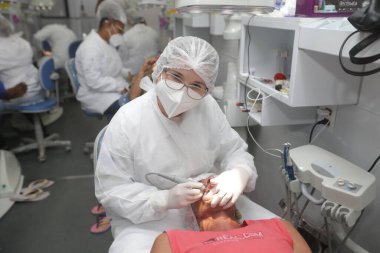 İlheus, Bahia, Brezilya - 1 Haziran 2022: dişçi muayenehanesinde bir hastaya diş tedavisi uygular..