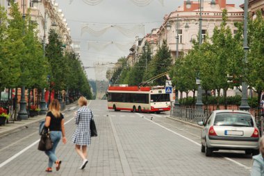 Şehirde bir cadde. Arabaları, tramvayları, yayaları olan ana yol. Vilnius, Litvanya. Şehir manzarası.