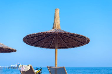 Denizin arka planında saman şemsiyesi.