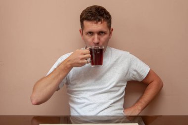 Genç adam masada siyah çay içer..