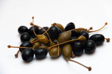 Beyaz arka planda siyah zeytin ve yeşil kapari..