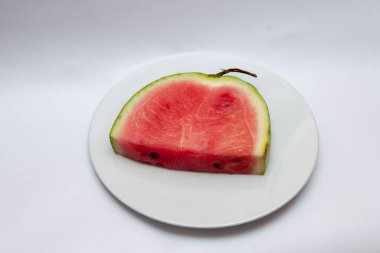 Beyaz arka planda beyaz bir tabakta bir parça karpuz izole edilmiş..