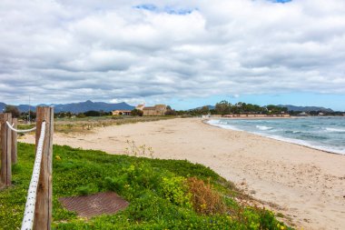Plaj, arka planda görünen kilise, Chiesa Romanica di Sant 'Efisio - Nora, eski kilise deniz kıyısında, Sardunya, İtalya