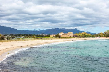 Plaj, arka planda görünen kilise, Chiesa Romanica di Sant 'Efisio - Nora, eski kilise deniz kıyısında, Sardunya, İtalya