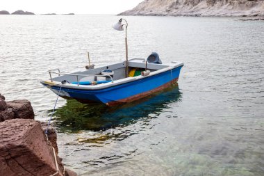 Güzel mavi tekne bir kayaya bağlandı.