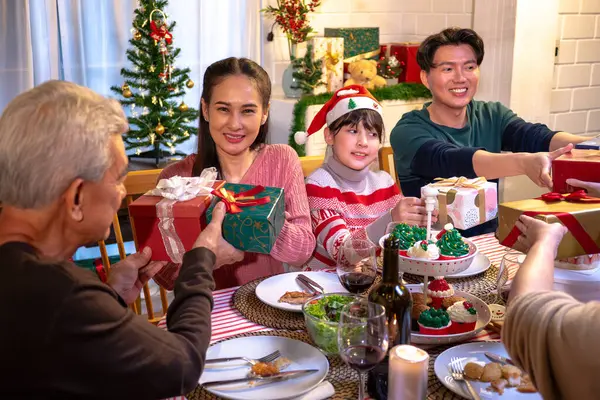 Happy people are celebrating on a table meal when christmas and new year at home. Cheerful elder , daughter ,son and child are eating dinner food with merry xmas decoration when happy new year holiday.