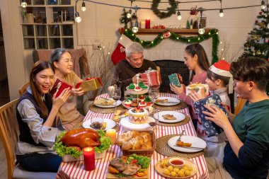 Mutlu insanlar Noel 'i ve evde yeni yılı masa yemeğinde kutluyorlar. Neşeli büyük, kız, kız, oğul ve çocuk, yeni yıl tatili mutlu geçtiğinde, mutlu bir Noel süsüsüyle akşam yemeği yiyorlar..