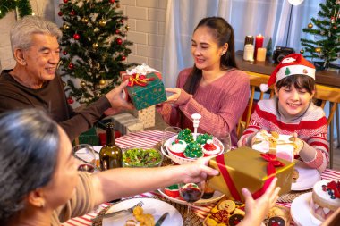 Mutlu insanlar Noel 'i ve evde yeni yılı masa yemeğinde kutluyorlar. Neşeli yaşlı, kız ve çocuk, mutlu bir yeni yıl tatili geçirdikleri zaman, mutlu bir Noel süsüsüyle akşam yemeği yiyorlar..