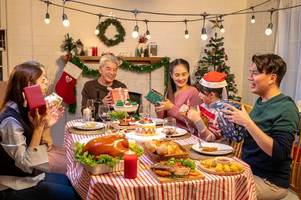Mutlu insanlar Noel 'i ve evde yeni yılı masa yemeğinde kutluyorlar. Neşeli yaşlı, kız ve çocuk, mutlu bir yeni yıl tatili geçirdikleri zaman, mutlu bir Noel süsüsüyle akşam yemeği yiyorlar..