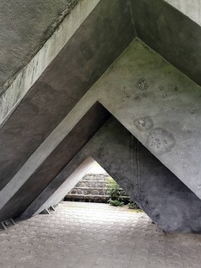 Beton ya da çimento yapılarının soyut ve geometrik bileşimi keskin açılar ve köşegen çizgiler oluşturarak, sonunda bir çıkış ya da yol gösteren bir geçit ya da tünel oluşturur. Maddenin kabataslak dokusu ve şablonlar.