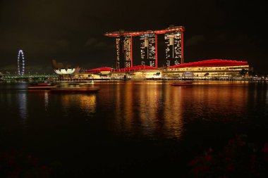 Nighttime view of Singapore from Merlion Park, overlooking Marina Bay Sands. Boats gently glide across the water, while the lights of Marina Bay create stunning reflections on its surface. clipart