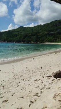 Kristal berrak suyu, beyaz kumlu kıyı şeridi ve kabarık bulutlu mavi gökyüzü güneşli bir günde - Seyşeller.