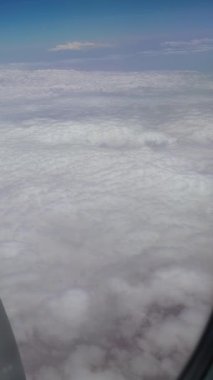 Ufuk boyunca uzanan uçsuz bucaksız kabarık beyaz bulutların geniş bir görüntüsü, bir uçak penceresinden çekildi. Dünya 'nın yüksek irtifada sakin ve nefes kesici bir görüntüsü..
