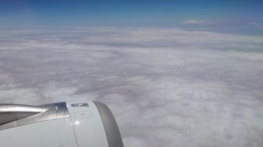 Ufuk boyunca uzanan sonsuz tüylü beyaz bulutların görüntüsü bir uçak penceresinden çekiliyor. Dünya 'nın yüksek irtifada sakin ve nefes kesici bir görüntüsü..