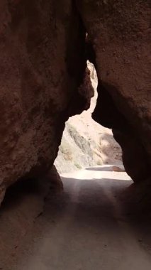 Yumuşak güneş ışığıyla aydınlatılan kırmızımsı kahverengi kayaların arasından oyulmuş göz kamaştırıcı dar bir kanyon yolu..