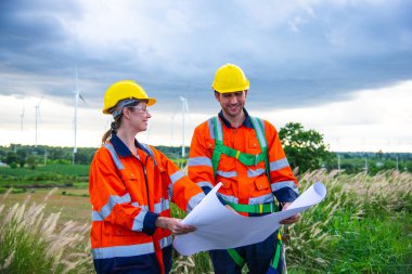 Rüzgar türbini çiftliğinde çalışan iki mühendis, sürdürülebilir enerji endüstrisi kavramı, iklim değişikliği için yenilenebilir enerji çözümü